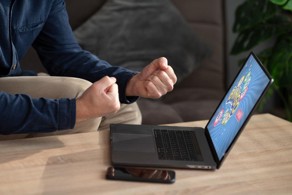 Alt: Person celebrating at laptop with game screen
